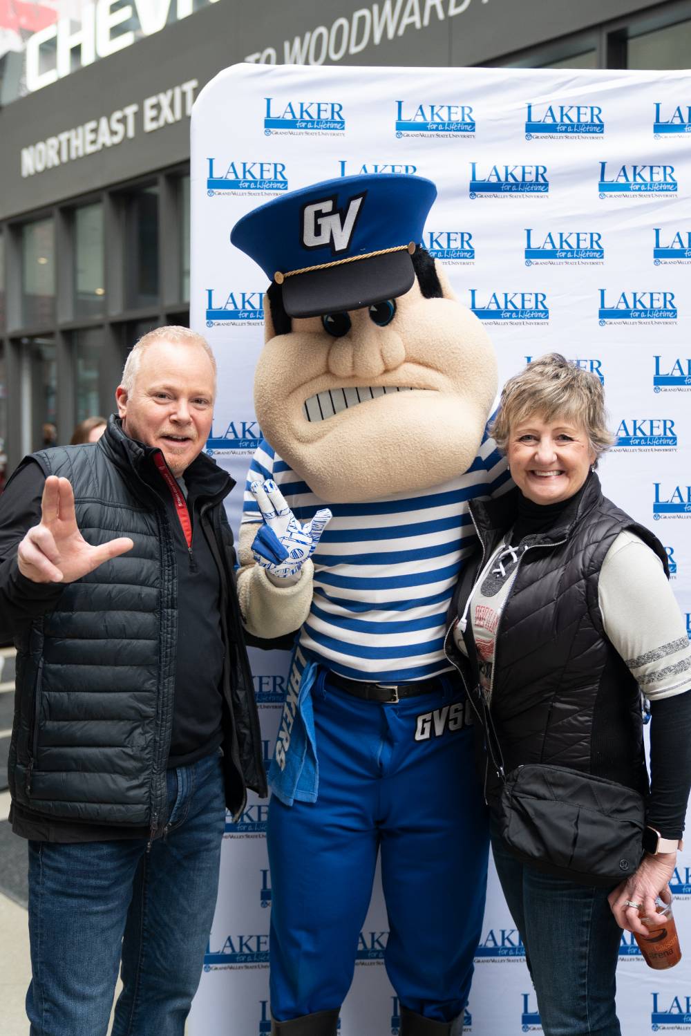 Two alumni pose with Louie the Laker